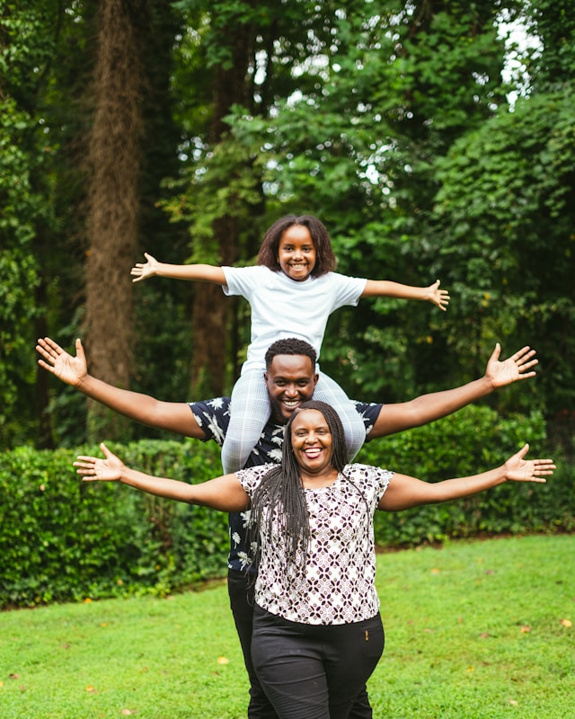A joyful family outdoors with arms spread wide